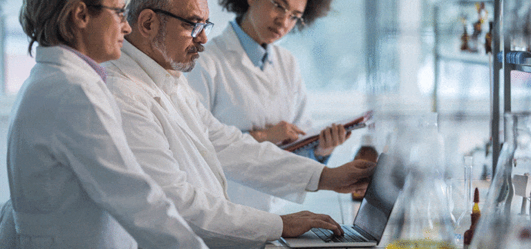 three laboratory workers looking at computer monitor photo for successful laboratory expansion case study