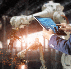 Person using tablet to check how machine robots are working in a factory