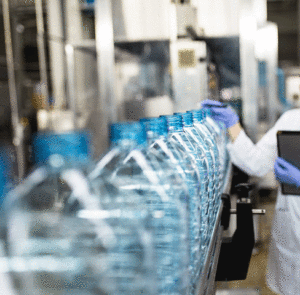 person checking the quality of a bottle at a manufacturing factory