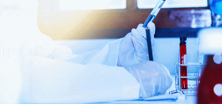 photo of laboratory worker looking at test tube and writing for IND submission case study