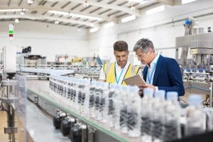 Consumer Products supervisor and manager watching plastic bottles on food and beverage manufacturing conveyor belt