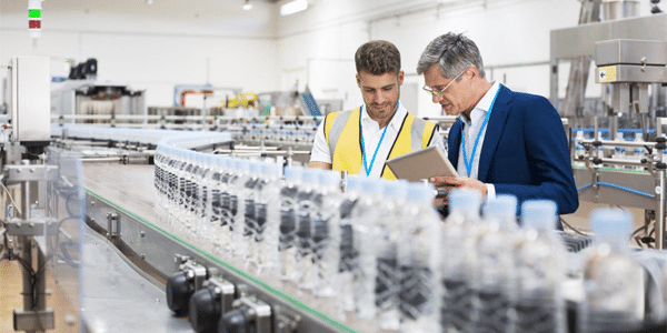 Consumer Products supervisor and manager watching plastic bottles on food and beverage manufacturing conveyor belt