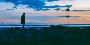 silhouette of person walking on rocks near body of water photo
